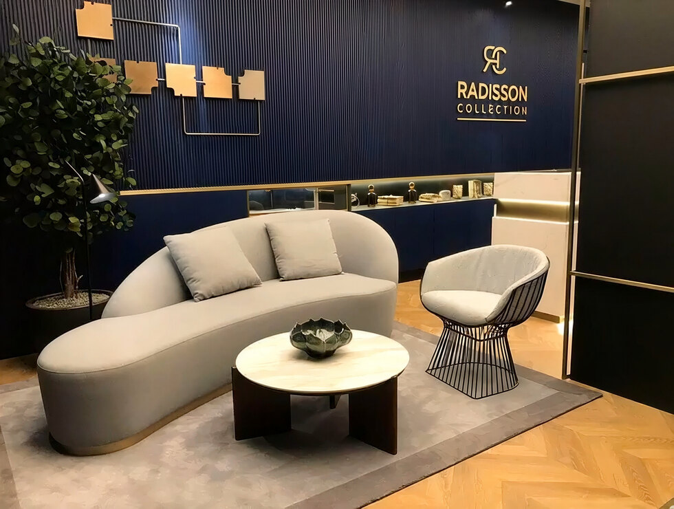 Sala de estar do Radisson Collection — sofá curvo com rodapé em latão.